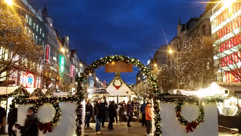 wenceslas square christmas market entry at night with a decorated archway entry and shops on both sides extending away into the distance