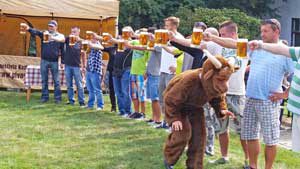 line of guys standing on grass holding a glass of beer at arms reach