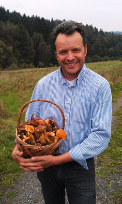 man with basket of mushrooms standing in a field