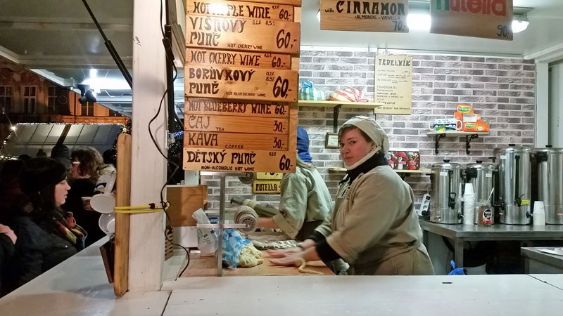 prague old town square hot drink stall with list of drinks and woman serving