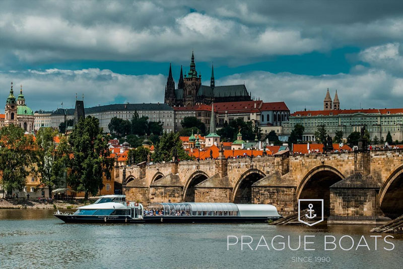 tour boat on the river vltava with the gothic stone charles bridge and prague castle in background