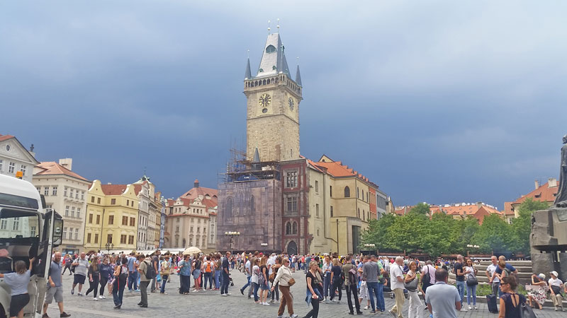 prague old town hall with crowd in front and black clouds behind