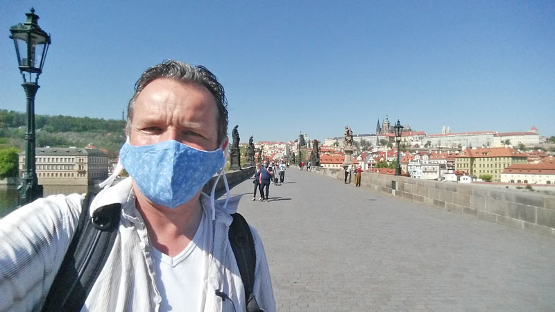 man standing on charles bridge in prague with mask