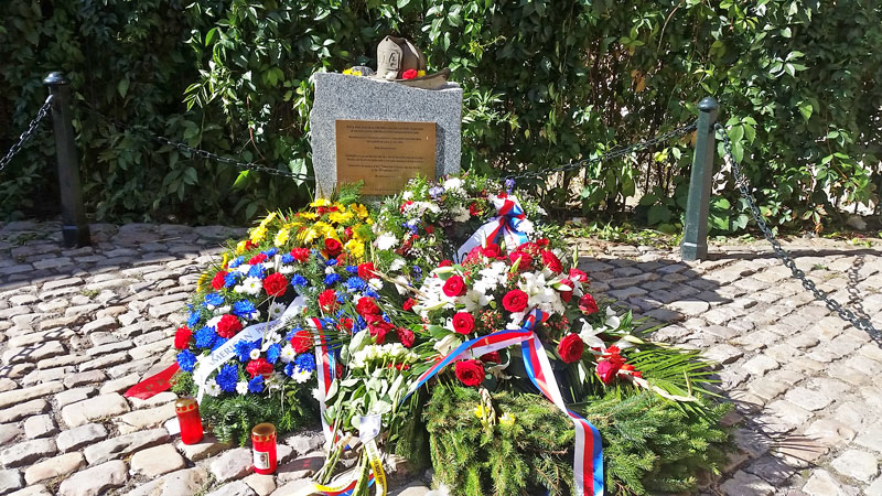 prague new york firefighters memorial. granite stone with plaque, helmet with the number 114 and flowers on a 9/11 anniversary