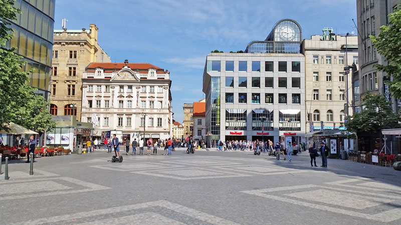 the pedestrianised bottom of prague wenceslas square with black and white cobbles. a mix of modern and old style buildings