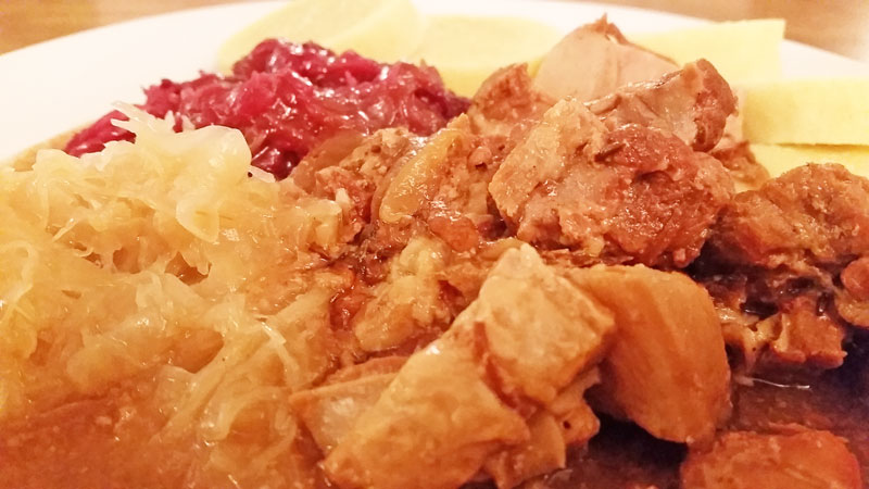 czech food called moravsky vrabec incuding pork with fat on the meat, red and white sweet cabbage and bread dumplings