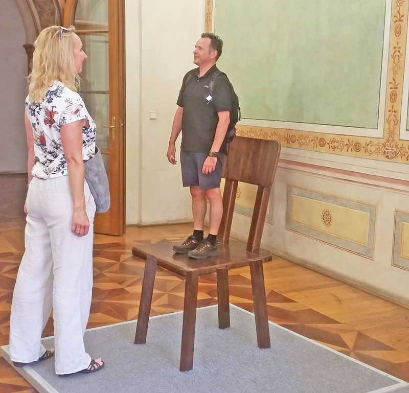 an exhibit at the prague illusion art museum that shows a man and a woman facing each other but the man appears much smaller