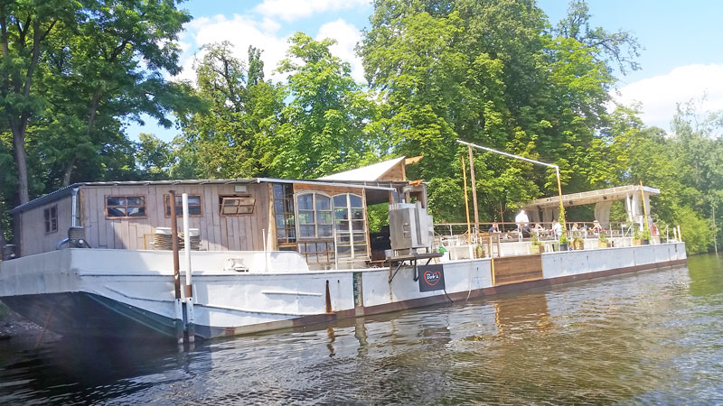 bobs bbq floating barge in prague moored against the tree covered shooters island