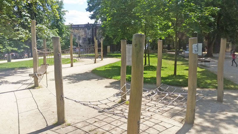 a series of wooden poles driven into the ground to act as connection points for ropes in a children's playground