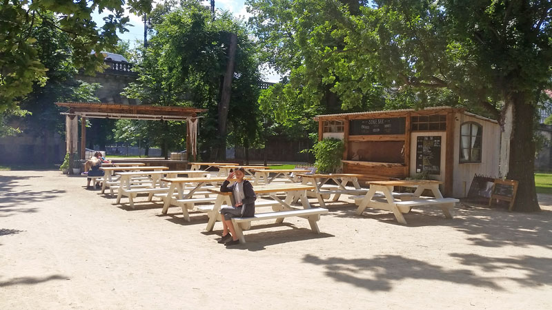 rough gravel area with ten picnic benches a bar on the right and a stage at the end