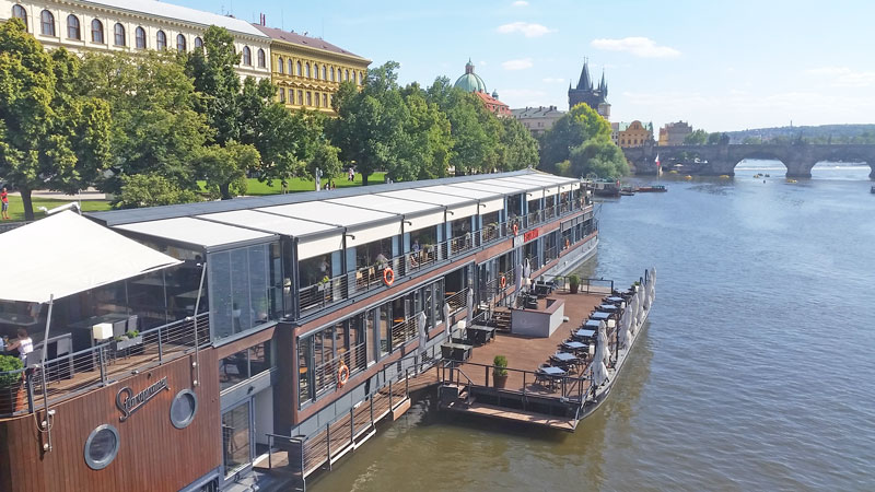 prague restaurant boat moored on the river vltava with charles bridge in the background