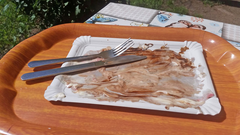 empty paper plate with knife and fork and some left over chocolate sauce