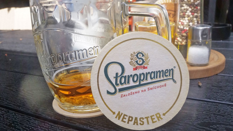 glass of staropramen beer with beer mat leaning against it