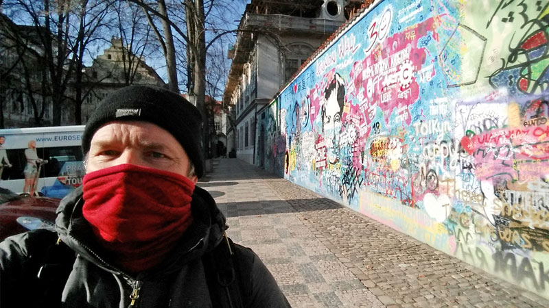 man standing all alone at the prague john lennon wall during the coronavirus lockdown