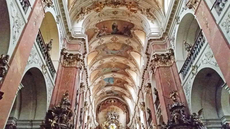 the interior of the baroque st james basilica in prague with marble columns and decorated knave