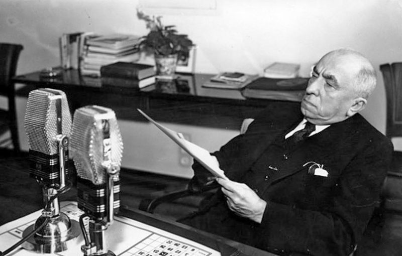 President Emil Hacha of Czechoslovakia seated at a table speaking into a microphone