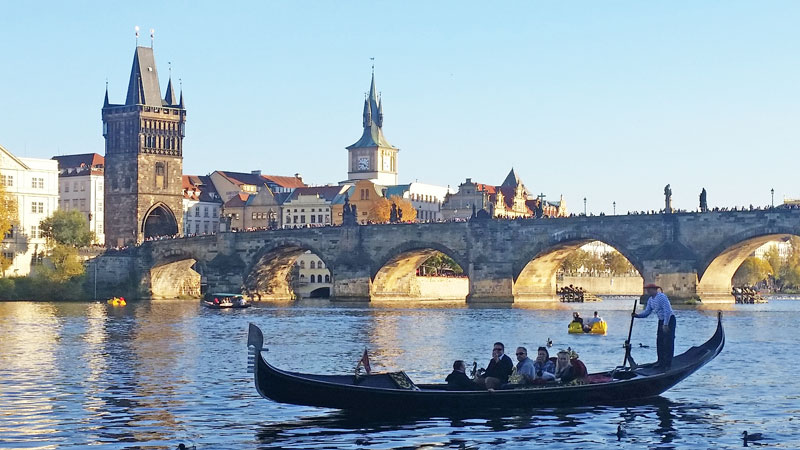 family on a gondola in Prague hired from Little Venice on the vltava river with charles bridge in the background