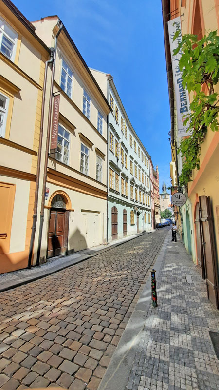 typical old town prague empty street scene with pretty cobbles, old houses and blue sky.