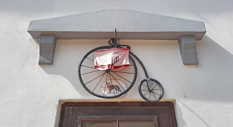 a model of a penny farthing bike above a door in the prague street called nový svět