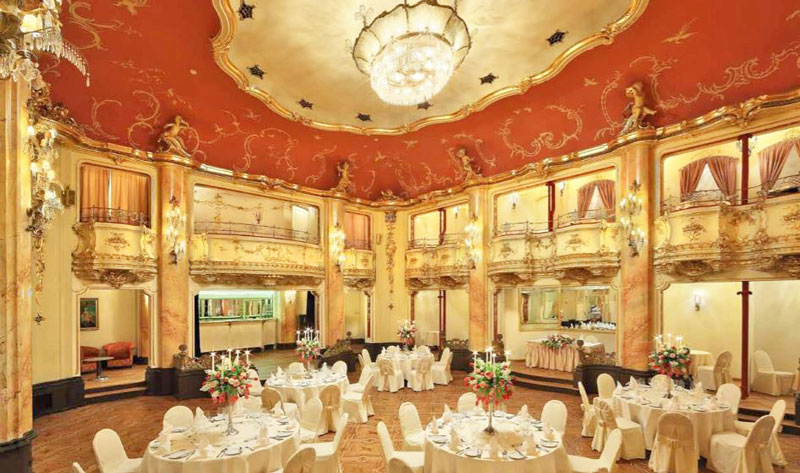 the neo-baroque style boccaccio ballroom in prague with inlaid hardwood floor, balconies and ceiling chandelier