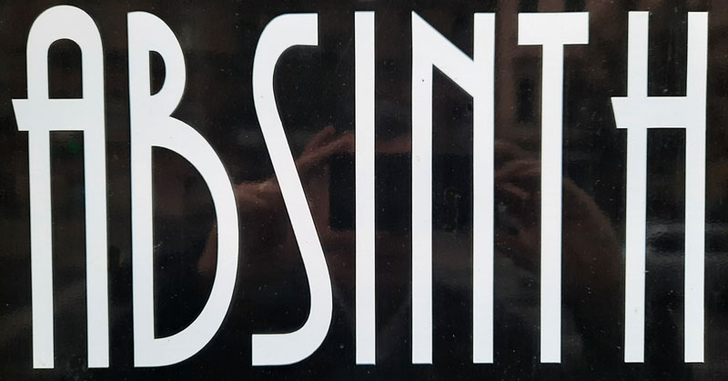 black and white sign in a shop window saying absinth in art deco style
