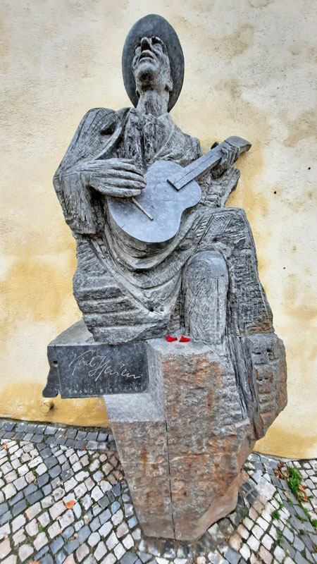 Karel Hašler playing a guitar statue on the Prague Old Castle Steps