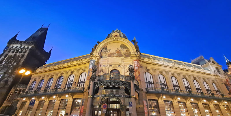 the facade of the municipal house in prague at night with the powder gate on the left