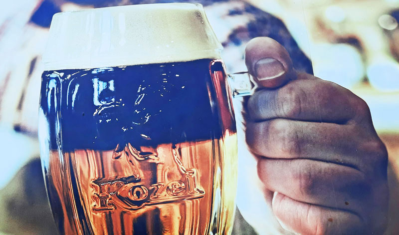 man holding a glass of beer that has dark beer at the top and light beer at the bottom which in Prague is called a cut beer