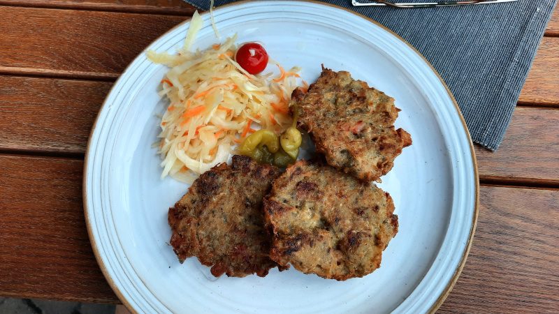 three pieces of czech bramboracky on a plate with sweet cabbage and peppers