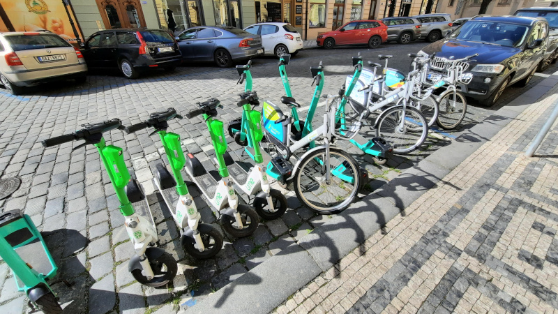 a row or e-scooters and e-bikes parked in an official prague city on-street hire parking bay