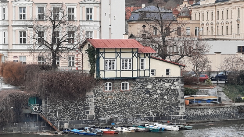 recent picture of a timber framed building on the riverside in prague which acted as an iron footbridge toll booth