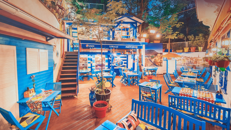 Luka Lu external summer garden with wooden floor and blue furniture